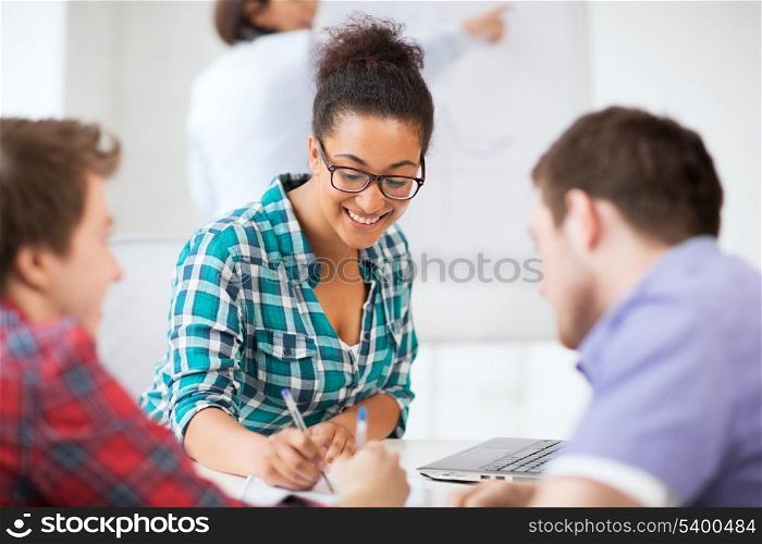 education concept - african student girl with laptop writing something in notebook