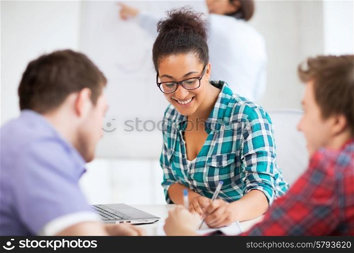 education concept - african student girl with laptop writing something in notebook