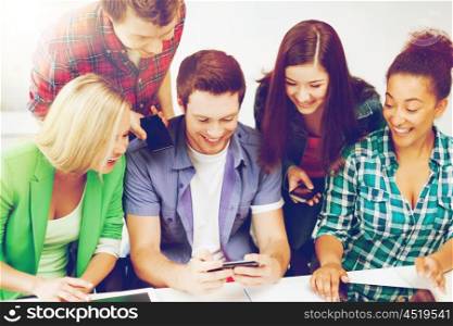 education concept - group of students looking into smartphone at school. students looking into smartphone at school