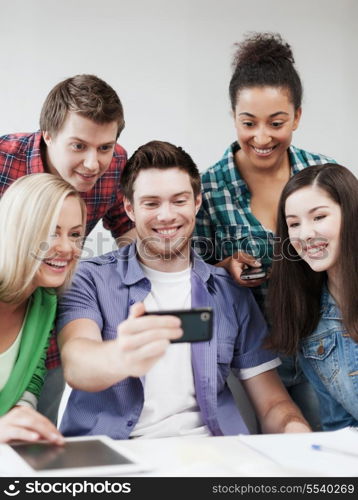 education concept - group of students looking into smartphone at school