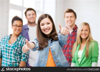 education concept - happy team of students showing thumbs up at school