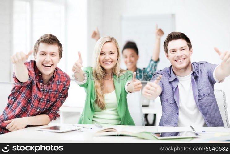 education concept - happy team of students showing thumbs up at school