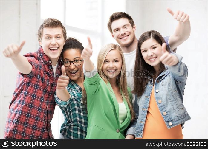 education concept - happy team of students showing thumbs up at school