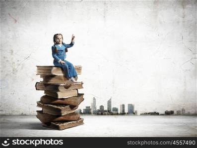 Education concept. Image of cute school girl in sitting on pile of books