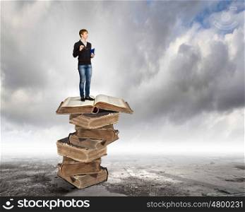 Education concept. Image of little cute boy standing on pile of books