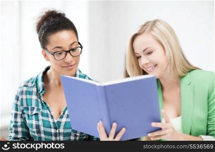 education concept - picture of smiling student girls reading book at school