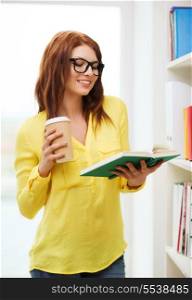 education concept - smiling redhead female student in eyeglasses with book and takeaway coffee in library