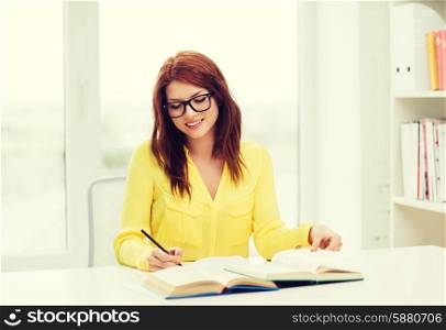 education concept - smiling student girl in eyeglasses reading books ana taking notes in library