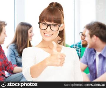 education concept - smiling student girl in glasses showing thumbs up at school
