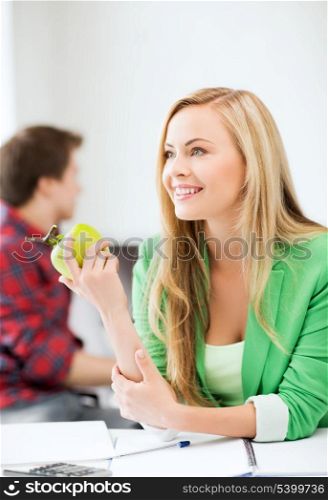 education concept - smiling student girl with green apple in college