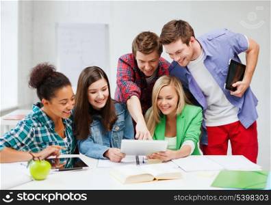 education concept - smiling students looking at tablet pc at school