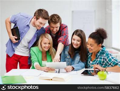 education concept - smiling students looking at tablet pc at school
