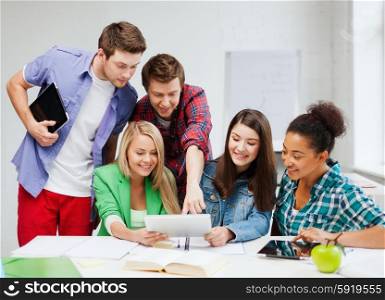 education concept - smiling students looking at tablet pc at school. students looking at tablet pc at school