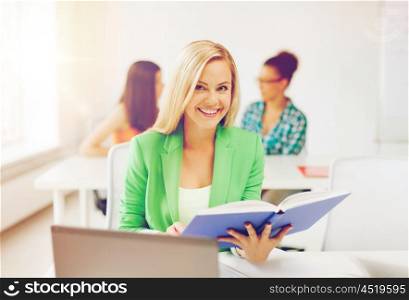 education concept - smiling young girl reading book at school. smiling young girl reading book at school