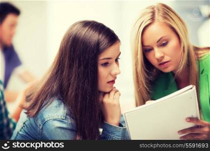 education concept - student girls looking at notebook at school