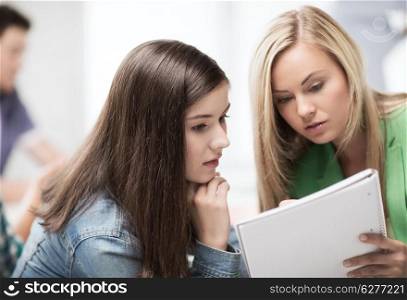 education concept - student girls looking at notebook at school