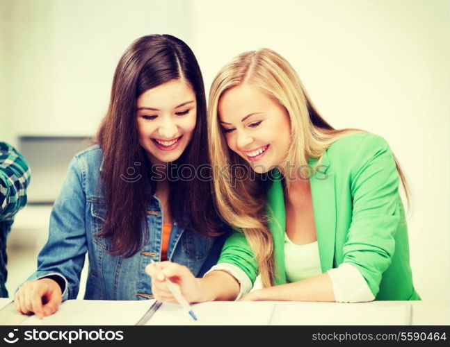 education concept - student girls pointing at notebook at school