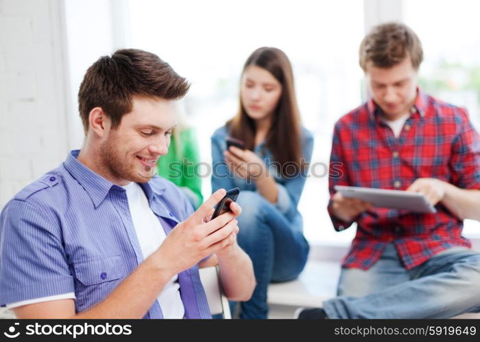 education concept - student looking into phone and writing at school. student looking into smartphone at school