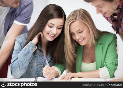 education concept - students pointing at notebook at school