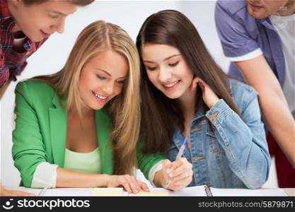 education concept - students pointing at notebook at school