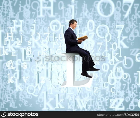 Education concept. Young businessman sitting on letter and reading book