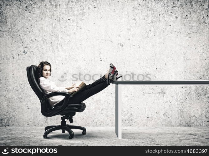 Education concept. Young businesswoman sitting in chair and reading book