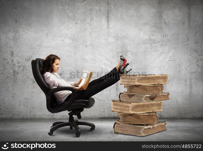 Education concept. Young businesswoman sitting in chair and reading book