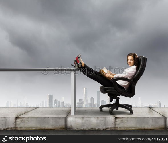 Education concept. Young businesswoman sitting in chair and reading book