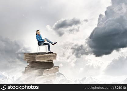 Education concept. Young girl sitting on high pile of books