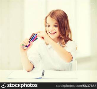 education, creation and school concept - smiling little student girl choosing colorful felt-tip pen at school