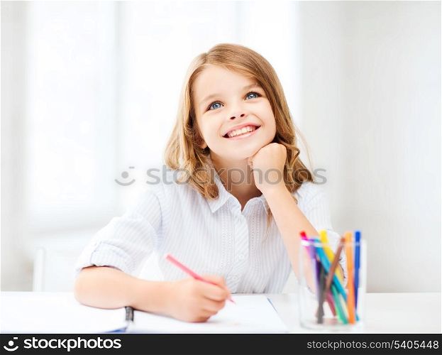 education, creation and school concept - smiling little student girl drawing and daydreaming at school