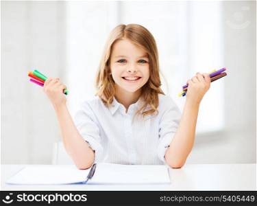 education, creation and school concept - smiling little student girl showing colorful felt-tip pens at school