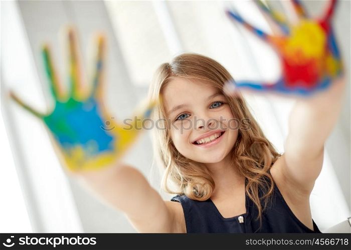 education, creation, art, people and children concept - happy girl showing painted hand palms at home