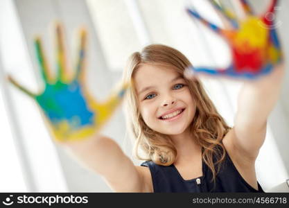 education, creation, art, people and children concept - happy girl showing painted hand palms at home