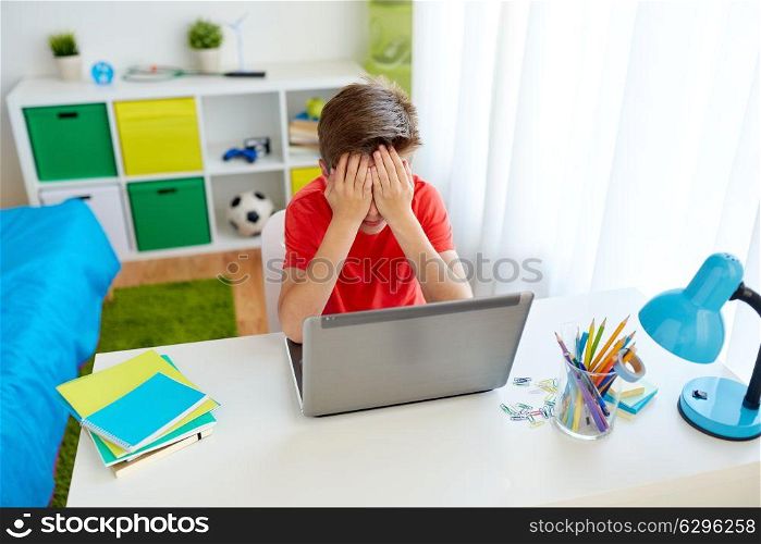 education, cyberbullying and people concept - upset student boy with on laptop computer at home suffering of bullying. upset student boy with laptop computer at home