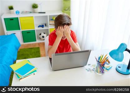 education, cyberbullying and people concept - upset student boy with on laptop computer at home suffering of bullying. upset student boy with laptop computer at home