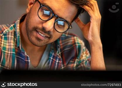 education, deadline and people concept - close up of creative man in glasses working at night office and thinking. close up of creative man working at night office