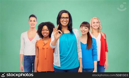 education, diversity and people concept - international group of happy smiling different women showing ok hand sign over green school chalk board background. international group of happy women showing ok