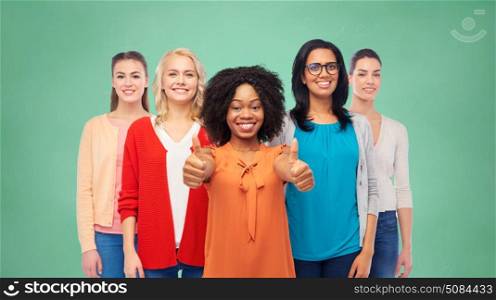 education, diversity and people concept - international group of happy smiling different women showing thumbs up over green school chalk board background. international group of women showing thumbs up. international group of women showing thumbs up