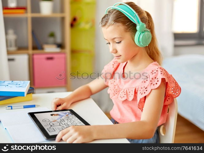 education, e-learning and school concept - happy student girl in headphones with teacher on tablet computer having online lesson at home desk. girl in headphones with tablet computer at home