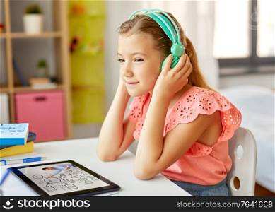education, e-learning and school concept - happy student girl in headphones with teacher on tablet computer having online lesson at home desk. girl in headphones with tablet computer at home