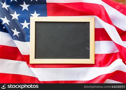 education, election, patriotism and nationalism concept - close up of blank school blackboard or chalkboard on american flag