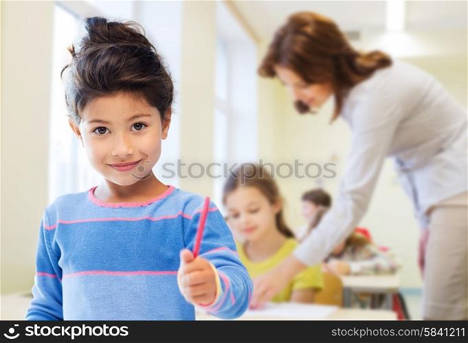education, elementary school and children concept - happy little student girl with pen over classroom and teacher background