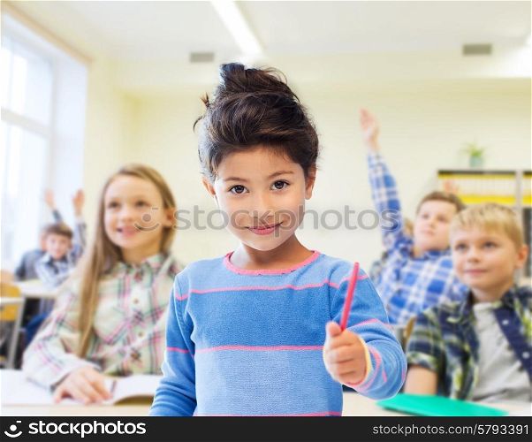 education, elementary school and children concept - happy little student with pen girl over classroom and classmates background