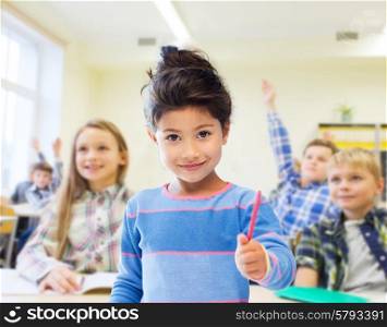 education, elementary school and children concept - happy little student with pen girl over classroom and classmates background