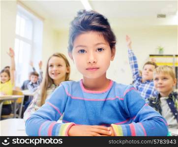 education, elementary school and children concept - little student girl over classroom and classmates background