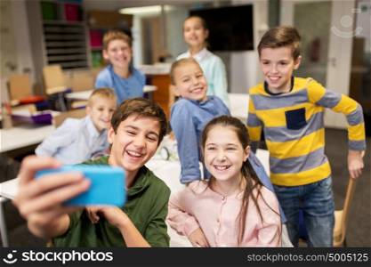 education, elementary school, children and people concept - group of kids taking selfie with smartphone in corridor. group of school kids taking selfie with smartphone