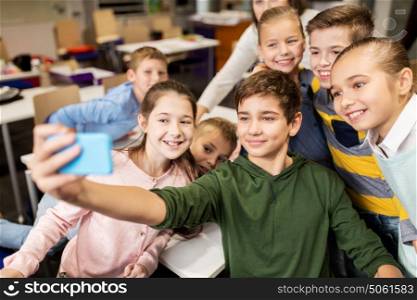 education, elementary school, children and people concept - group of kids taking selfie with smartphone in corridor. group of school kids taking selfie with smartphone
