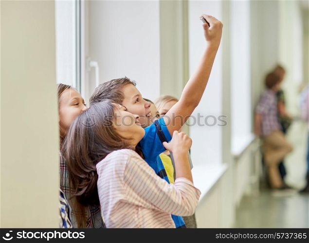 education, elementary school, drinks, children and people concept - group of school kids taking selfie with smartphone in corridor