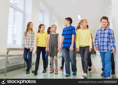 education, elementary school, drinks, children and people concept - group of smiling school kids walking in corridor